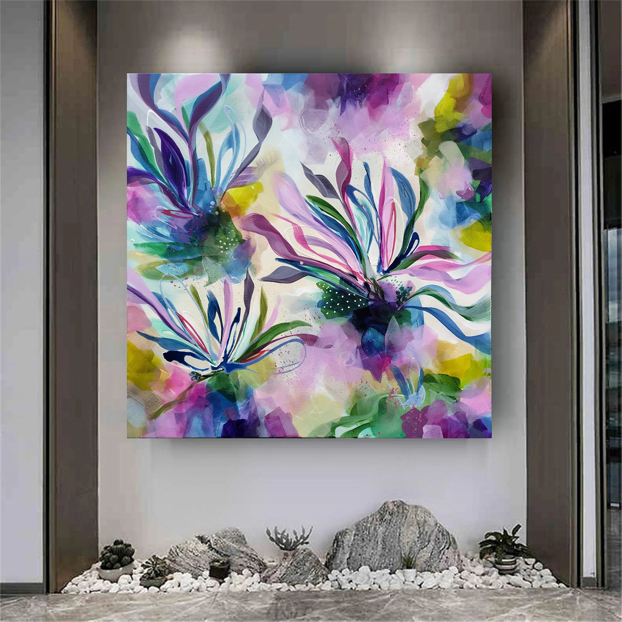 Colorful abstract painting on a wall with decorative stones and plants at the base.