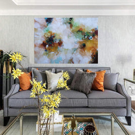 Gray sofa with colorful pillows in a living room setting with abstract art on the wall.