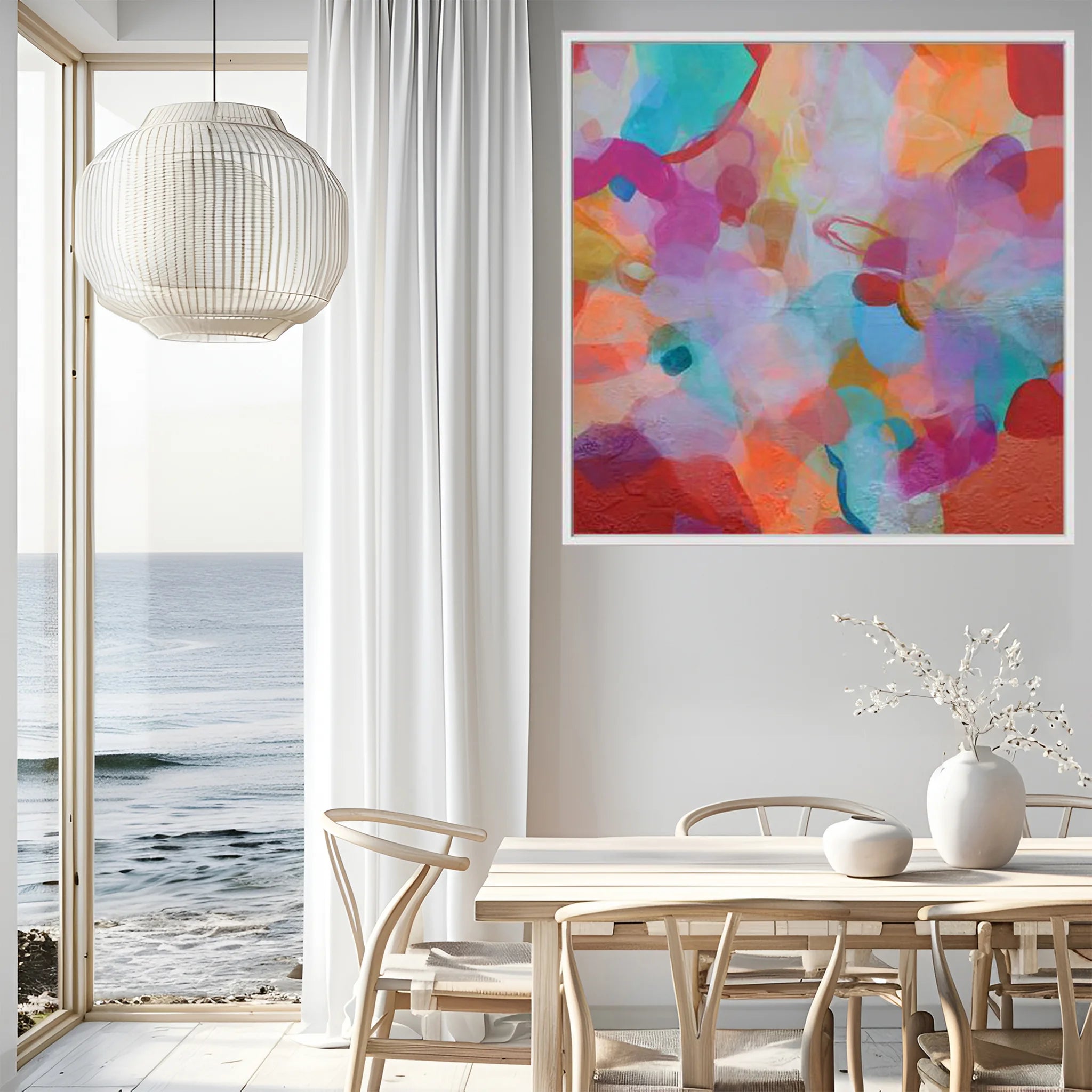 Modern interior with a colorful abstract painting on the wall, a dining table, and chairs by a large window with a view of the ocean.