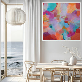 Modern interior with a colorful abstract painting on the wall, a dining table, and chairs by a large window with a view of the ocean.