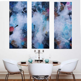 Three abstract wall art pieces above a dining table with chairs.
