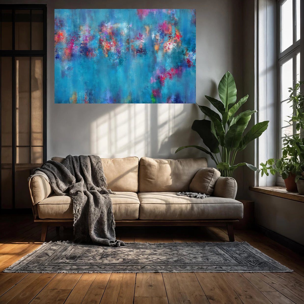 An abstract canvas wall art print featuring vibrant blue, pink, and purple brushstrokes, displayed in a modern living room setting above a beige sofa.