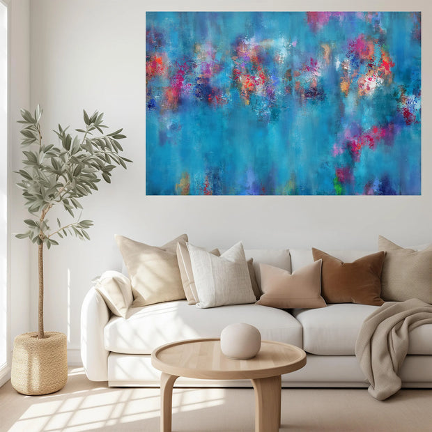 A large abstract canvas print featuring vibrant blue, purple, and pink brushstrokes, displayed on a white wall above a modern white sofa in a bright, contemporary living room.