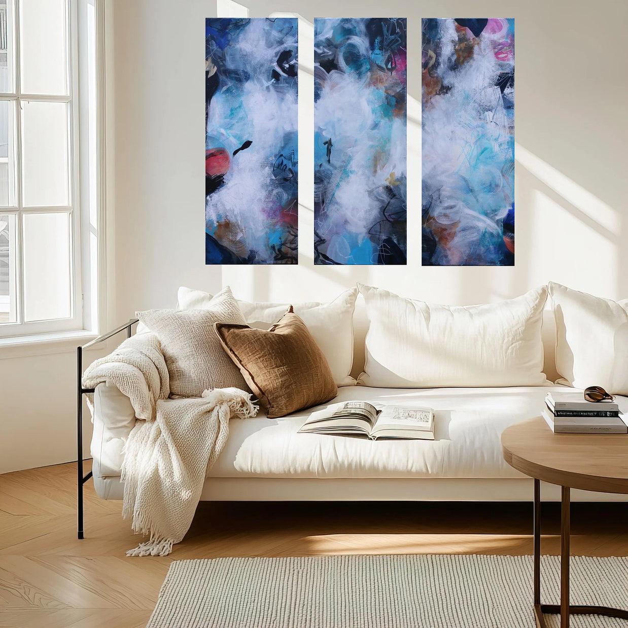 Three abstract paintings above a white sofa in a living room.