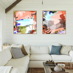 Living room with a white sofa, colorful abstract paintings on the wall, and decorative items on a coffee table.