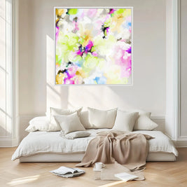 Colorful abstract painting on a white wall above a bed with pillows and a blanket.