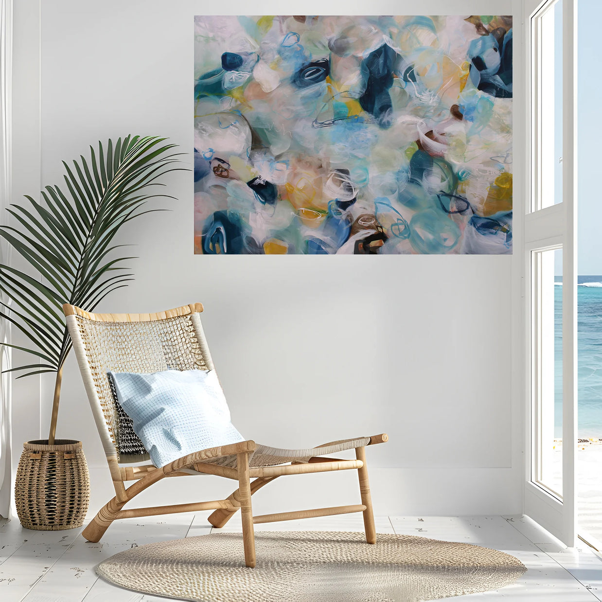 Modern interior with a wicker chair, abstract painting, and view of the ocean.
