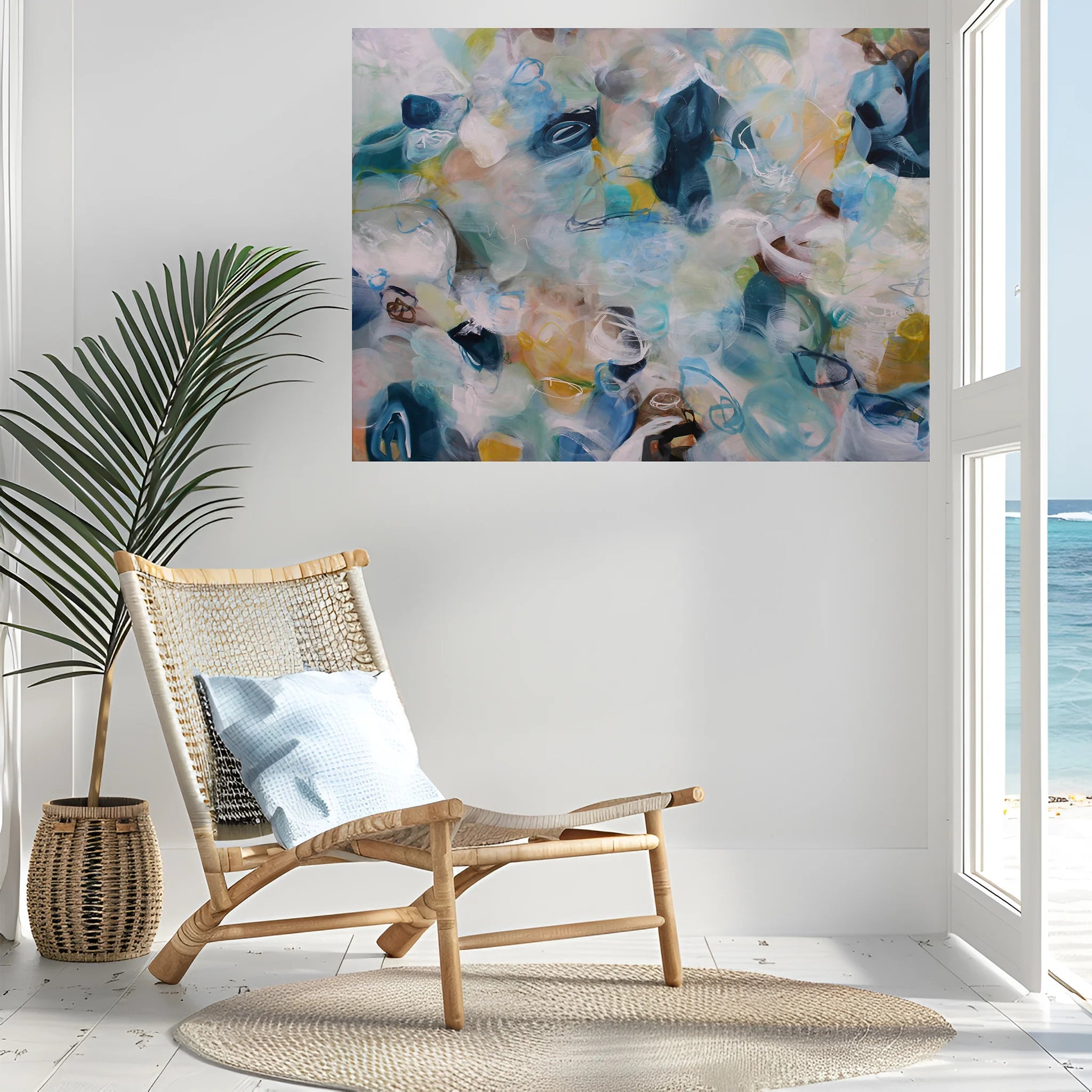 Modern interior with a wicker chair, abstract painting, and view of the ocean.