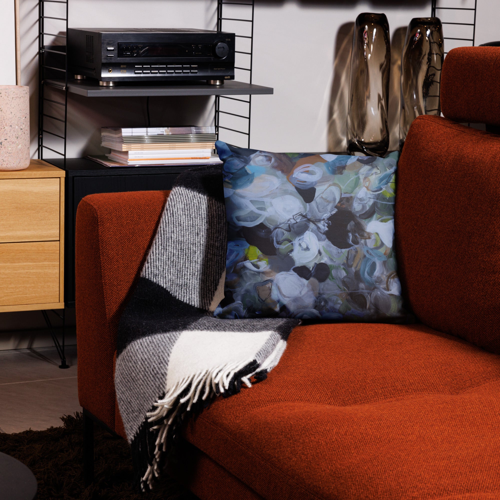 Orange sofa with decorative pillows and a blanket in a living room setting.
