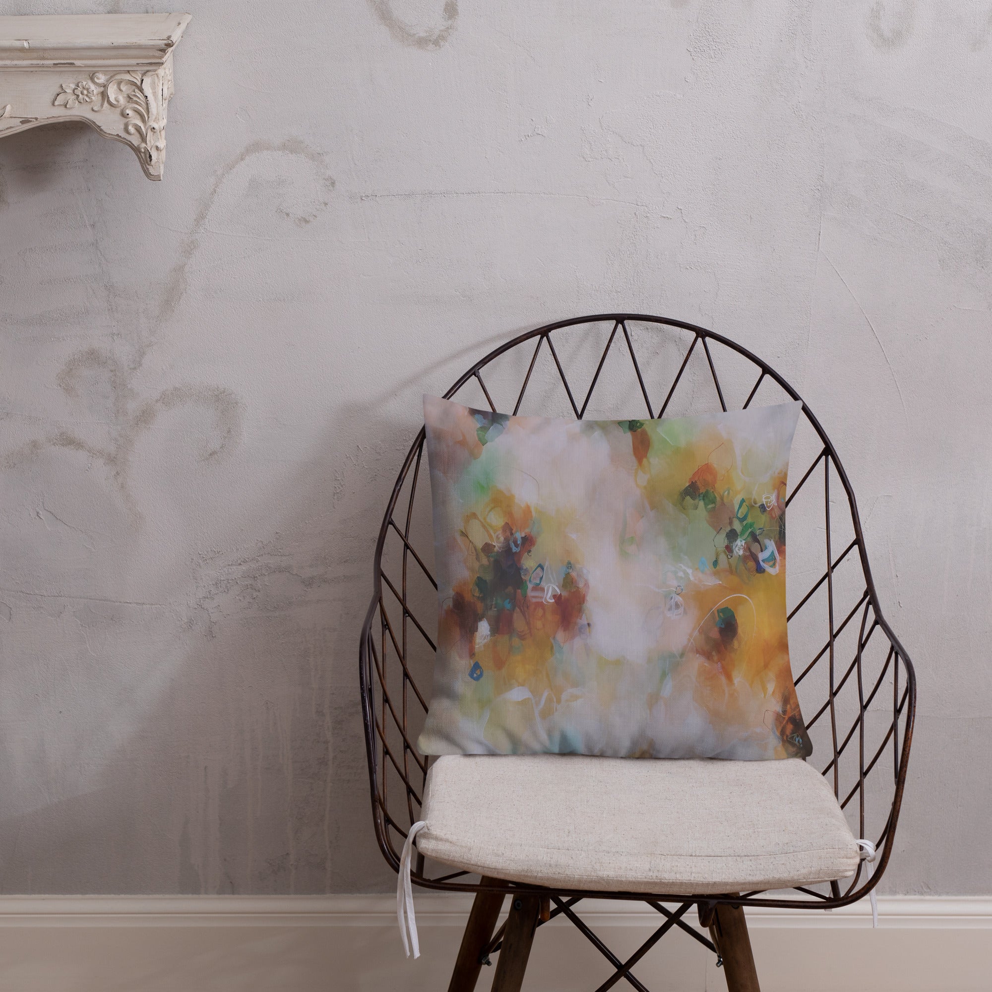 Decorative pillow with a floral pattern on a wire chair against a textured wall.