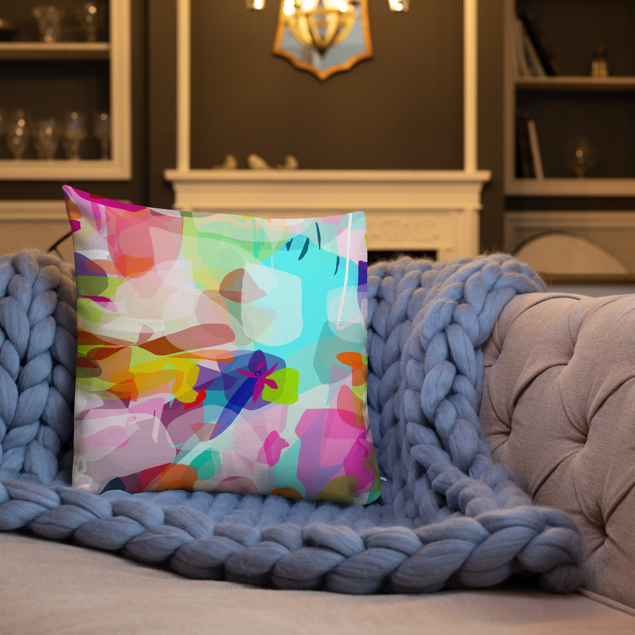 Colorful abstract pillow on a couch with a blue textured throw blanket