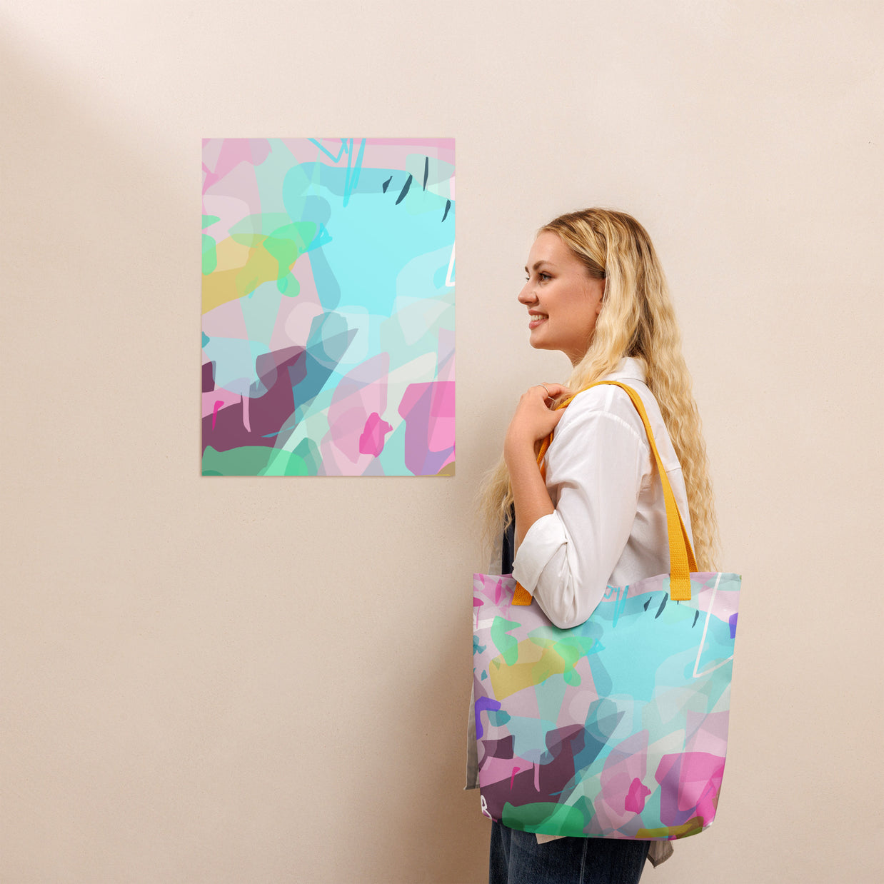 Woman holding a colorful tote bag with abstract design, standing next to a similar abstract painting on a beige wall.