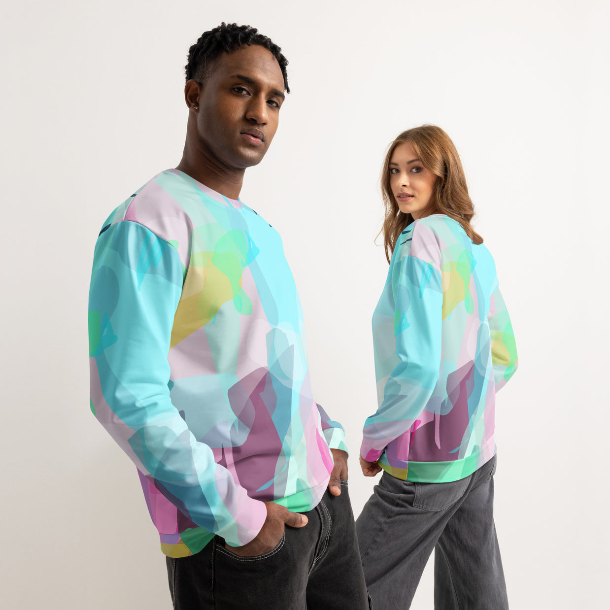 Two people wearing colorful tie-dye sweatshirts against a plain background