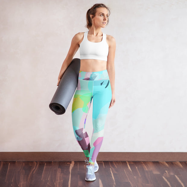 Woman holding a yoga mat wearing colorful leggings and a white sports bra.