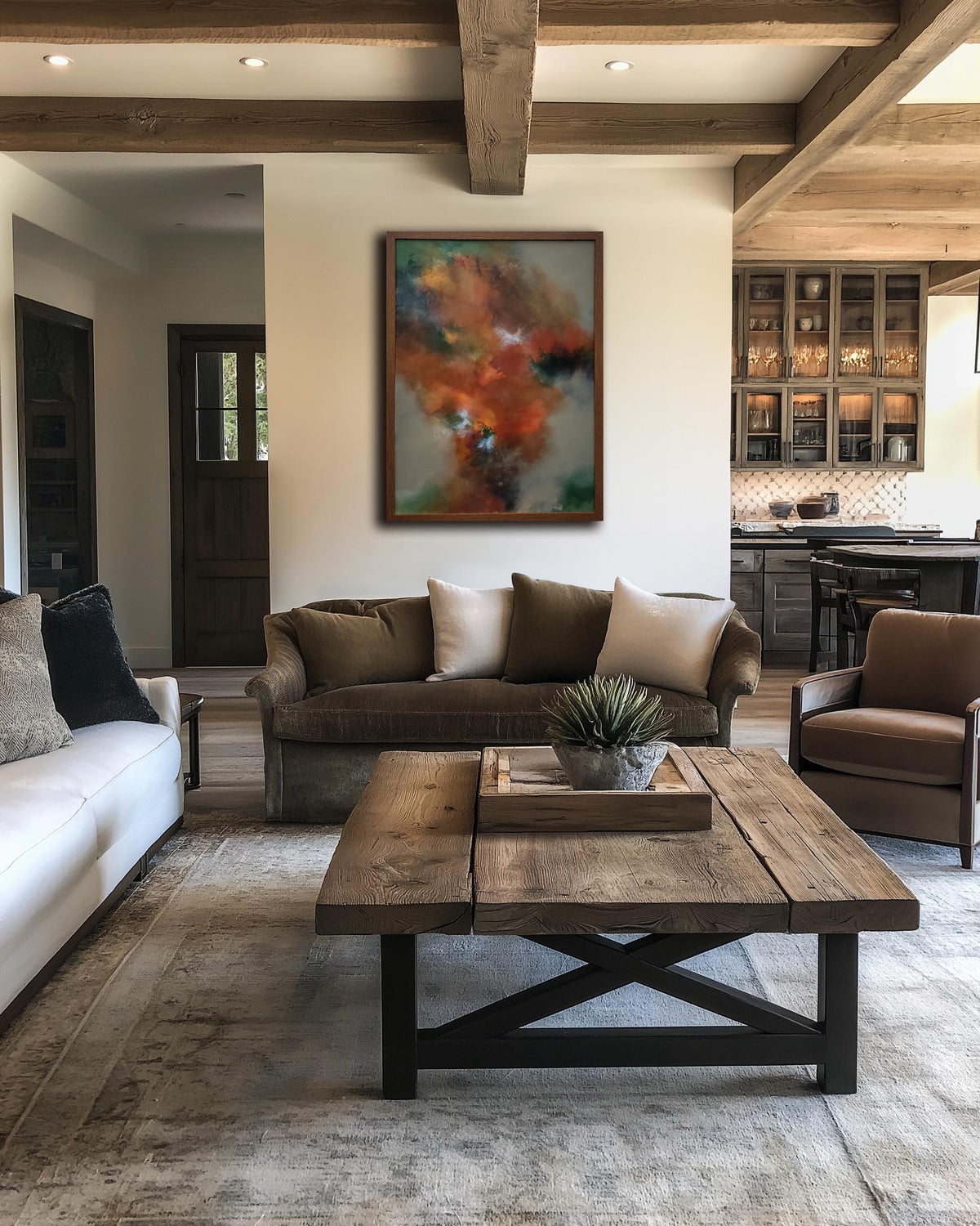 A rustic wooden coffee table in a modern farmhouse-style living room, positioned in front of a brown sofa and a large abstract painting on the wall.