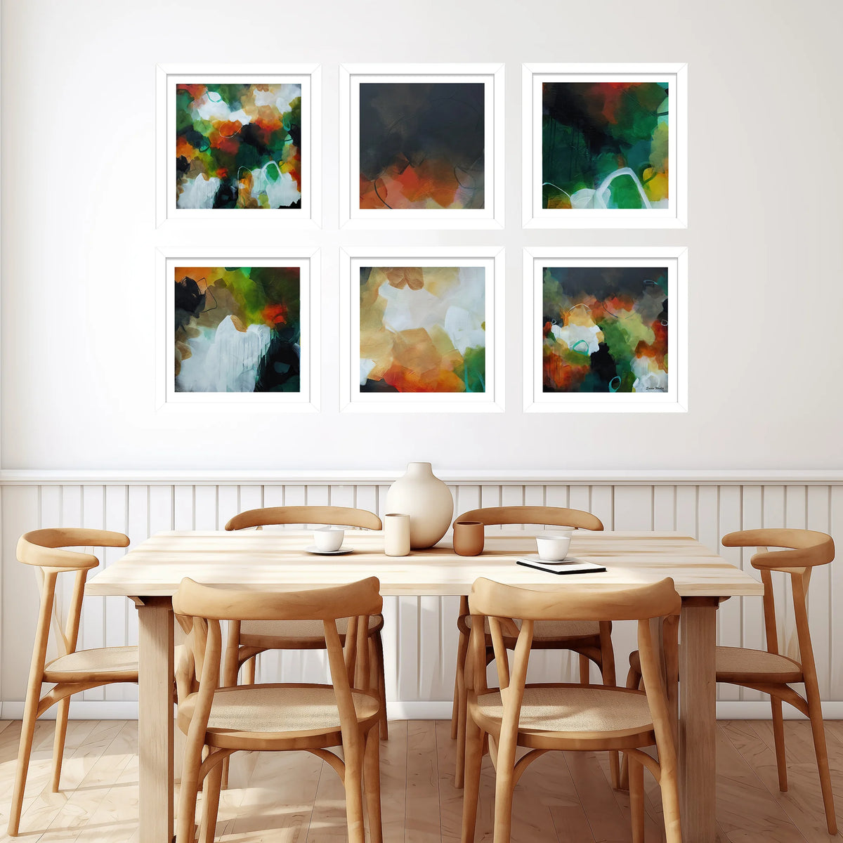 Six framed abstract paintings in a 2x3 grid on a white wall above a light wood dining table and six wooden chairs.