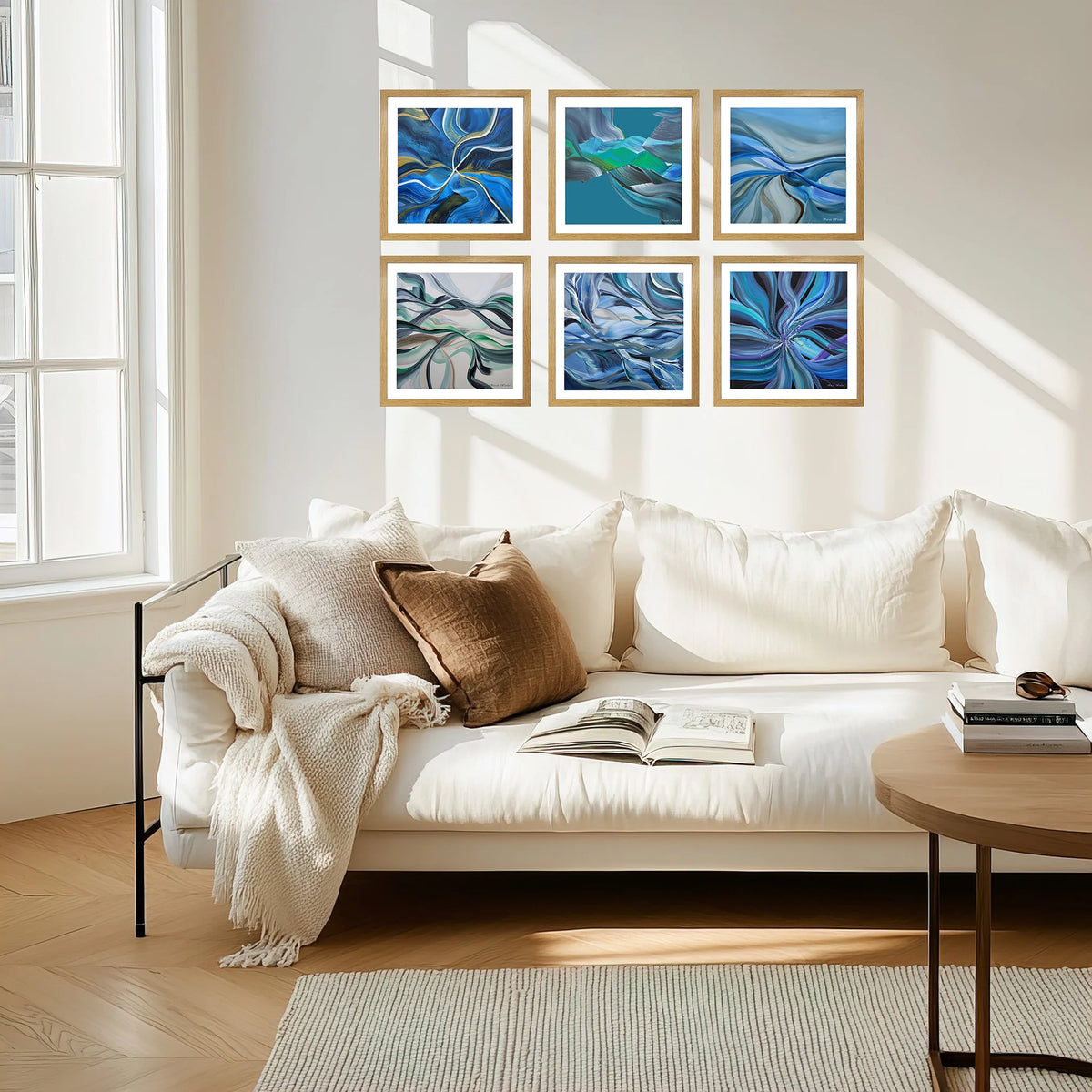 Six framed abstract blue wall art prints arranged in two rows above a white sofa in a bright, modern living room.