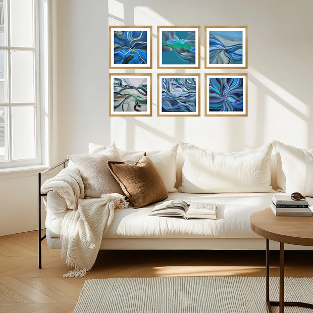 Six framed abstract blue wall art prints arranged in two rows above a white sofa in a bright, modern living room.