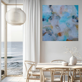 Modern interior with abstract art, table, chairs, and ocean view.