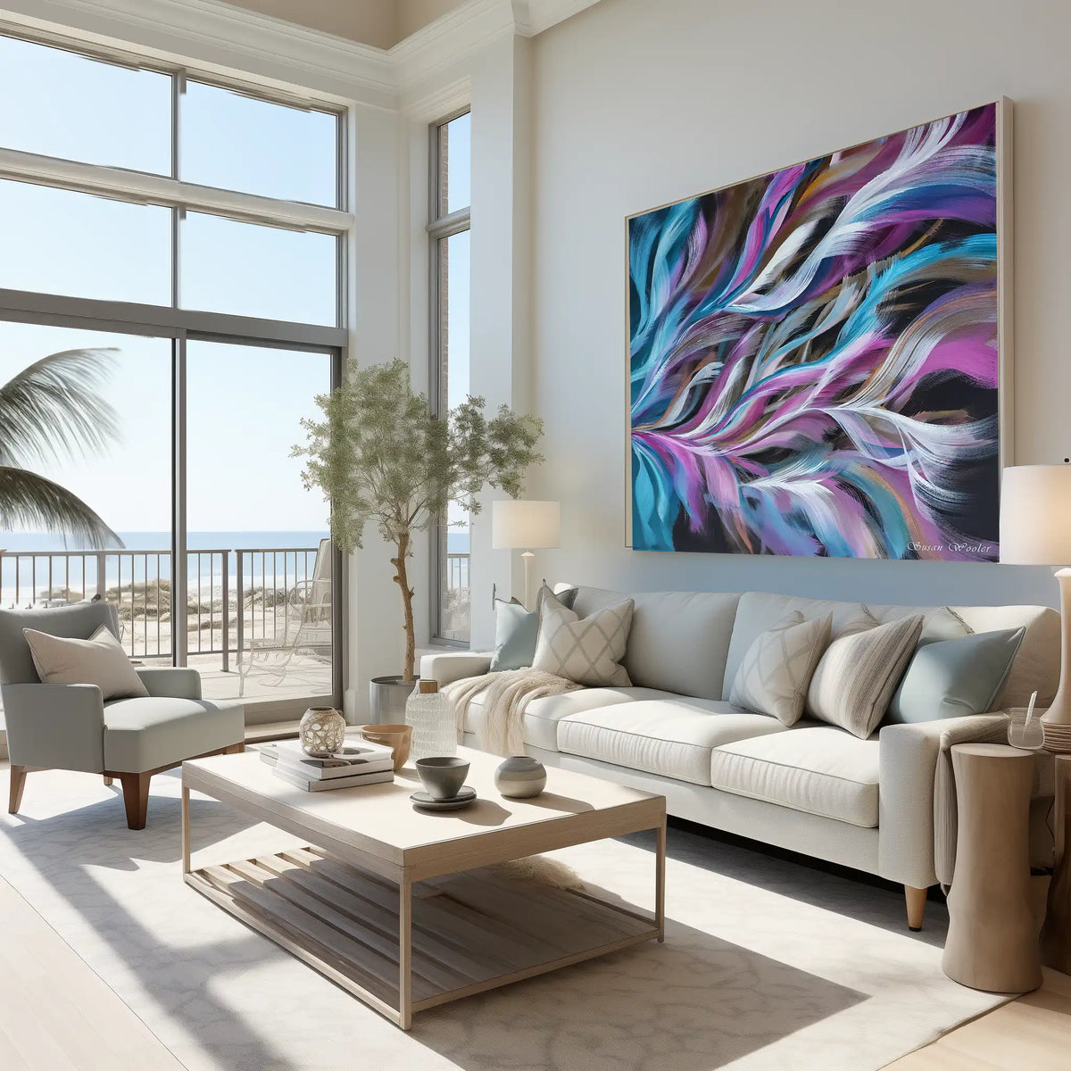 A large abstract canvas wall art print with swirling purple, blue, teal, and black brushstrokes hangs above a light beige sofa in a bright, modern living room with an ocean view.