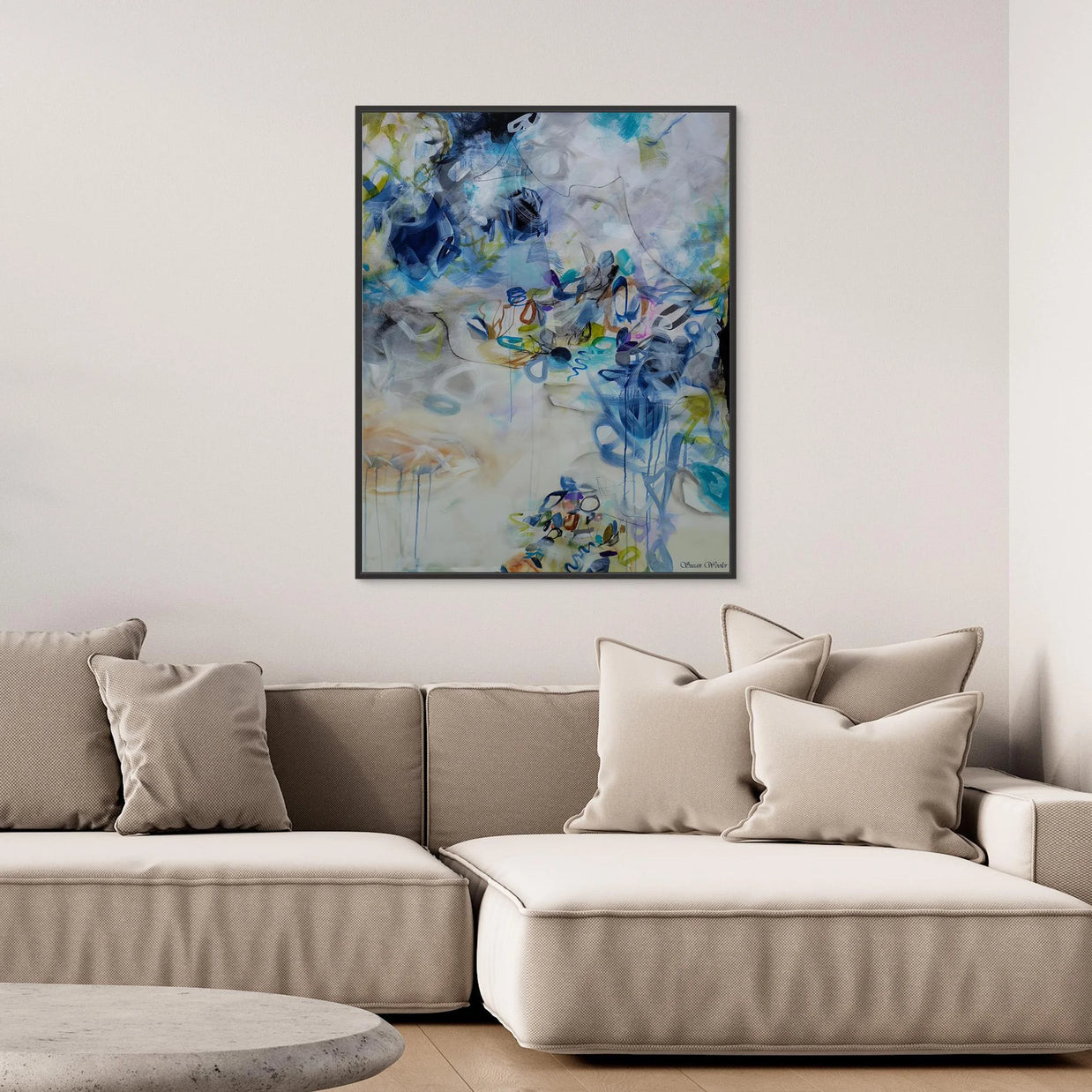 Beige sectional sofa with decorative pillows and a colorful abstract painting on the wall.