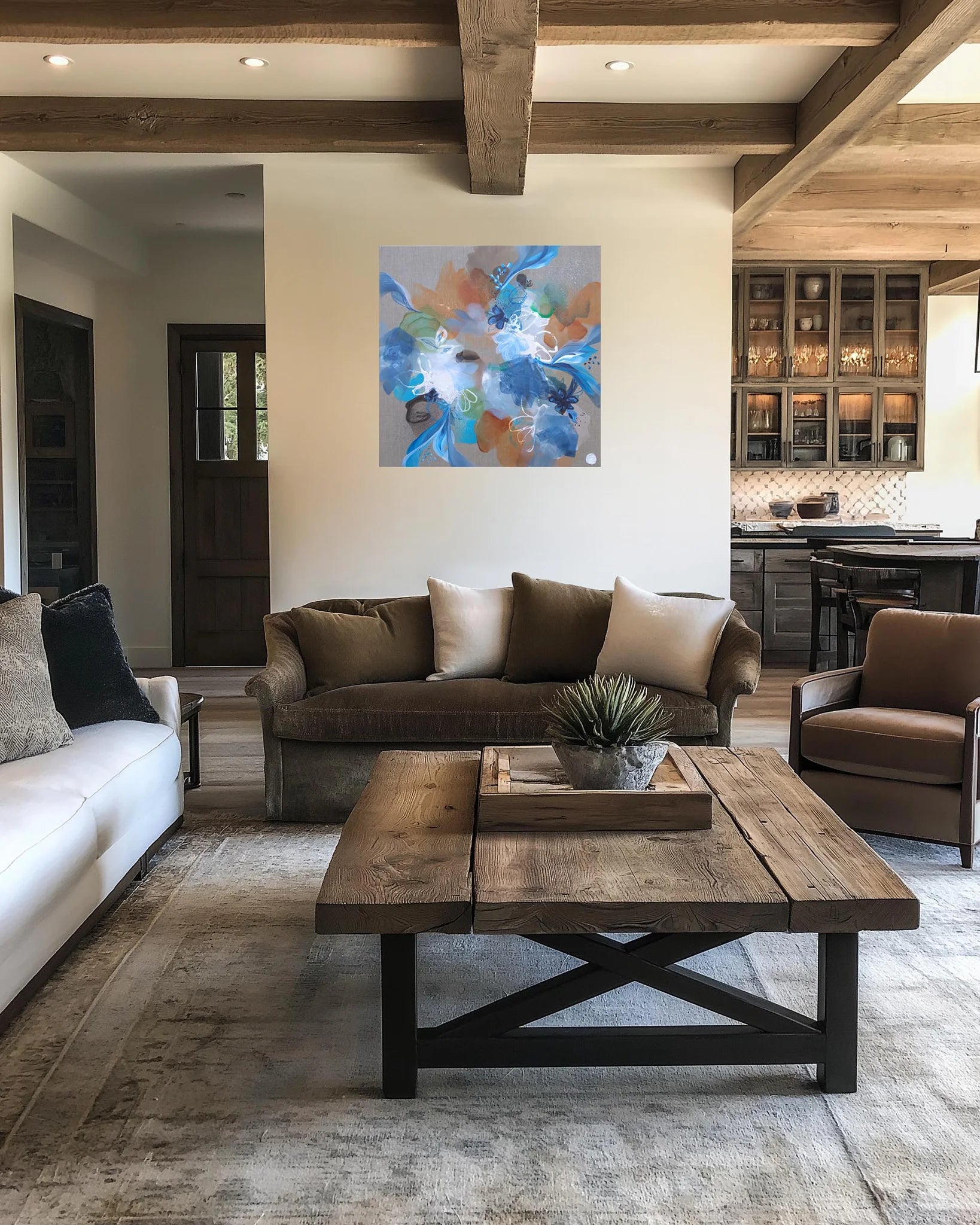 Modern living room with brown sofa, white rug, and abstract painting on wall.