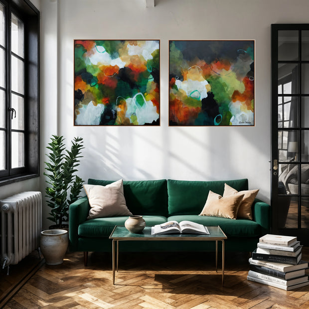 A modern living room scene with a green velvet sofa, wood herringbone floor, and two large framed abstract wall art prints hanging above the couch. The artwork features blended abstract shapes in green, orange, black, white, and yellow.