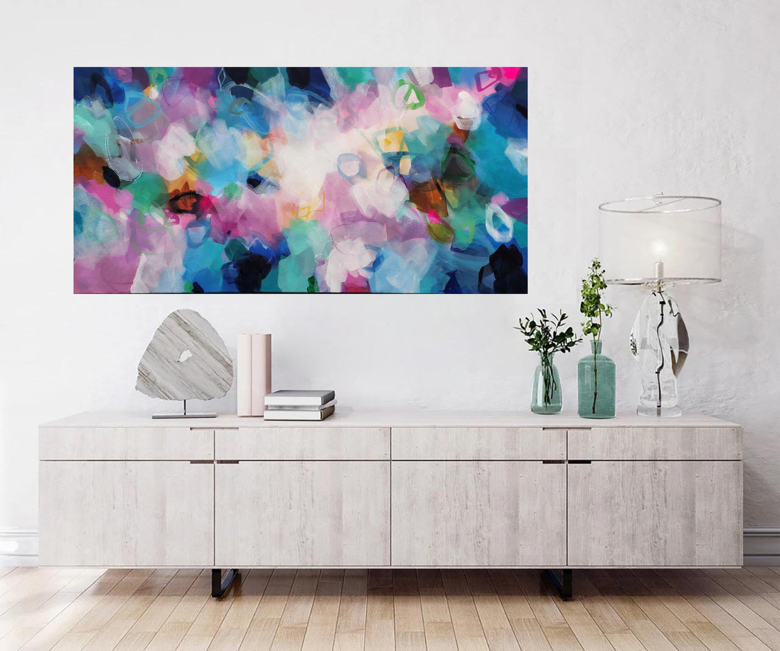 Modern living room with a colorful abstract painting above a wooden cabinet.