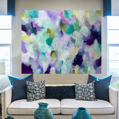 Living room with a colorful abstract painting above a beige sofa with blue and patterned cushions.