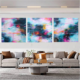 Abstract art triptych on a wall above a sofa in a living room