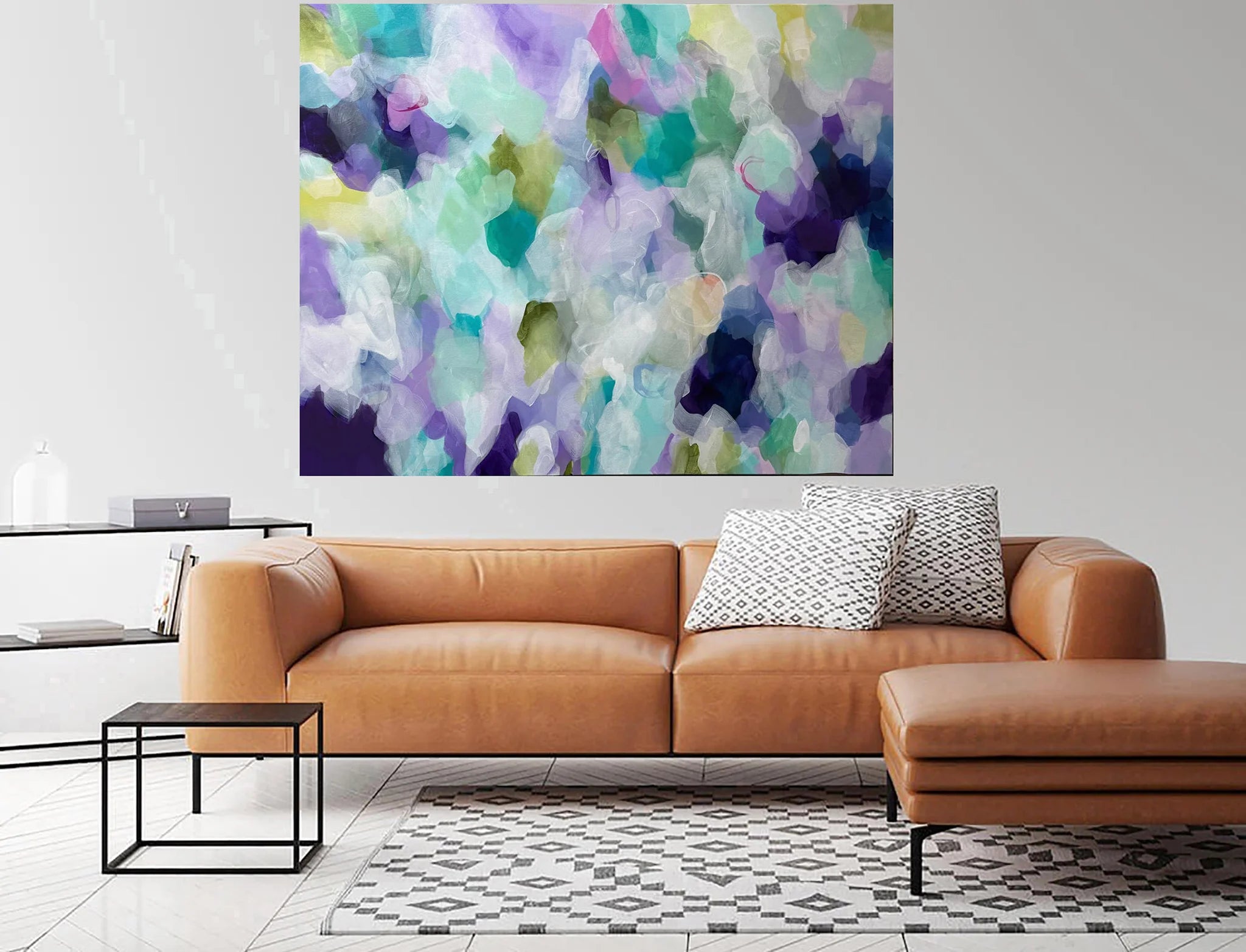 Modern living room with a brown leather sofa, abstract painting, and side table.