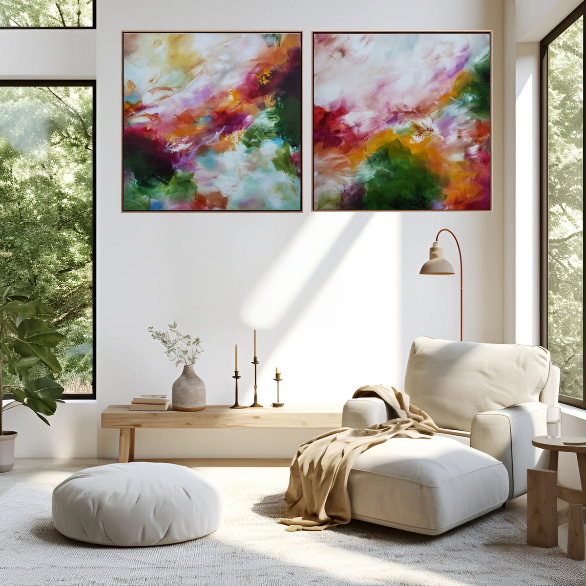A modern living room with two large abstract canvas prints hanging side by side on a white wall. The artwork features vibrant, painterly swirls of pink, purple, orange, green, and gold.