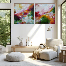 A modern living room with two large abstract canvas prints hanging side by side on a white wall. The artwork features vibrant, painterly swirls of pink, purple, orange, green, and gold.