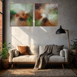 Two abstract canvas prints with earthy brown, green, and cream tones hanging side-by-side on a textured gray wall above a modern beige sofa in a styled living room.