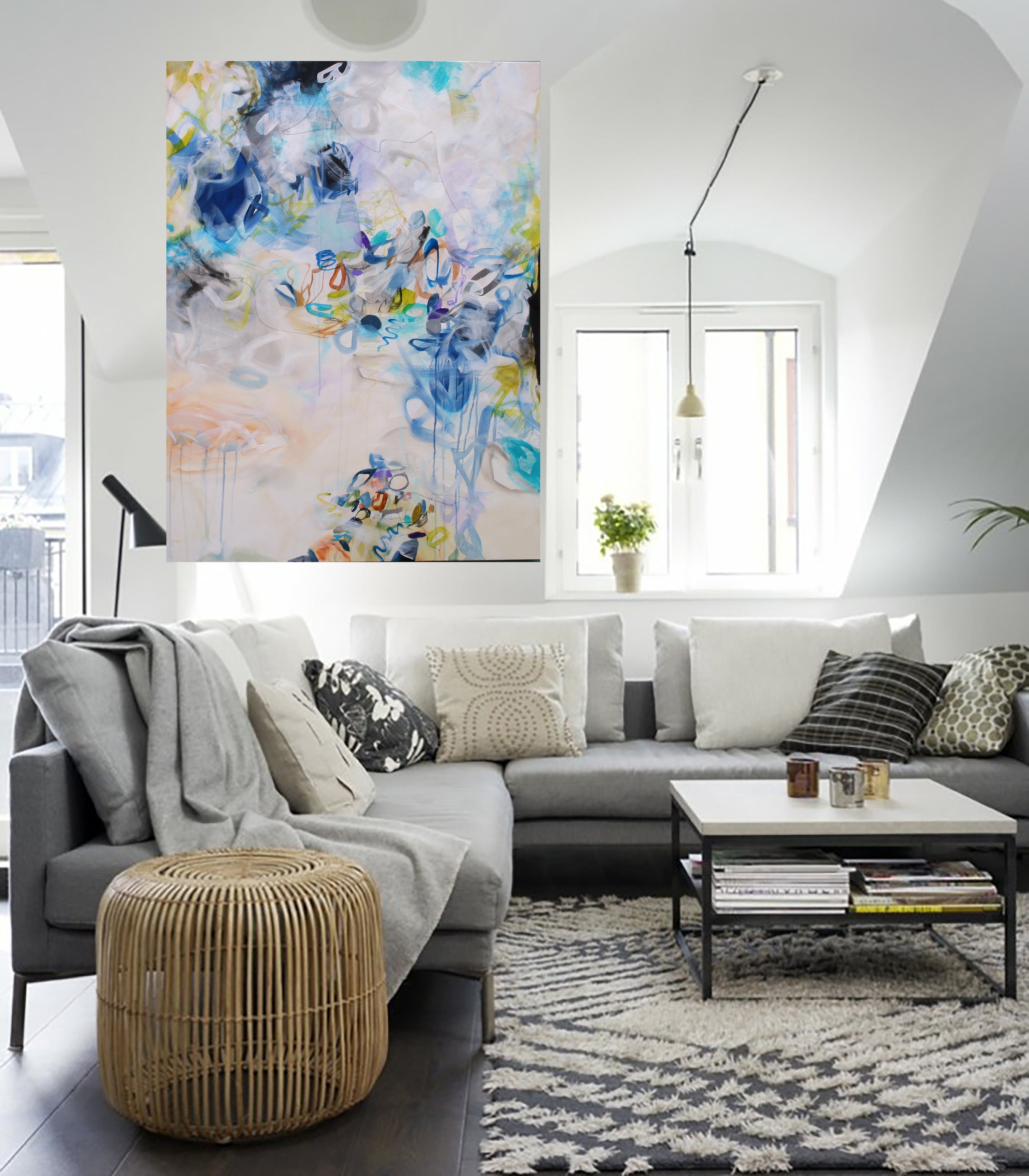 Modern living room with a gray sectional sofa, wicker ottoman, and abstract artwork on the wall.