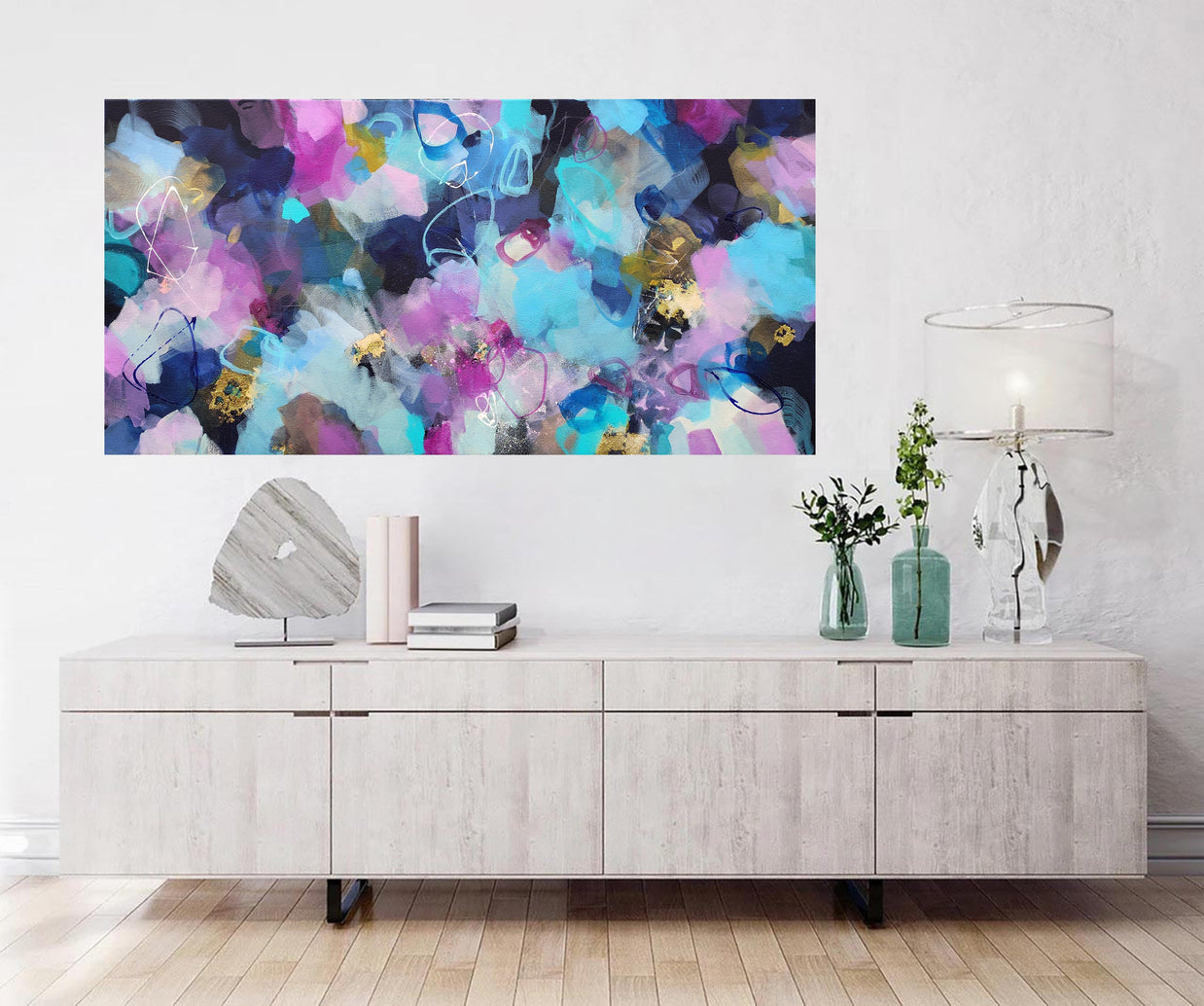 Abstract colorful painting on a wall above a wooden cabinet.