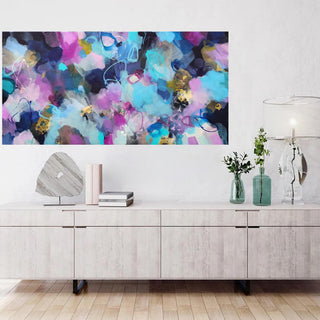 Abstract colorful painting on a wall above a wooden cabinet.