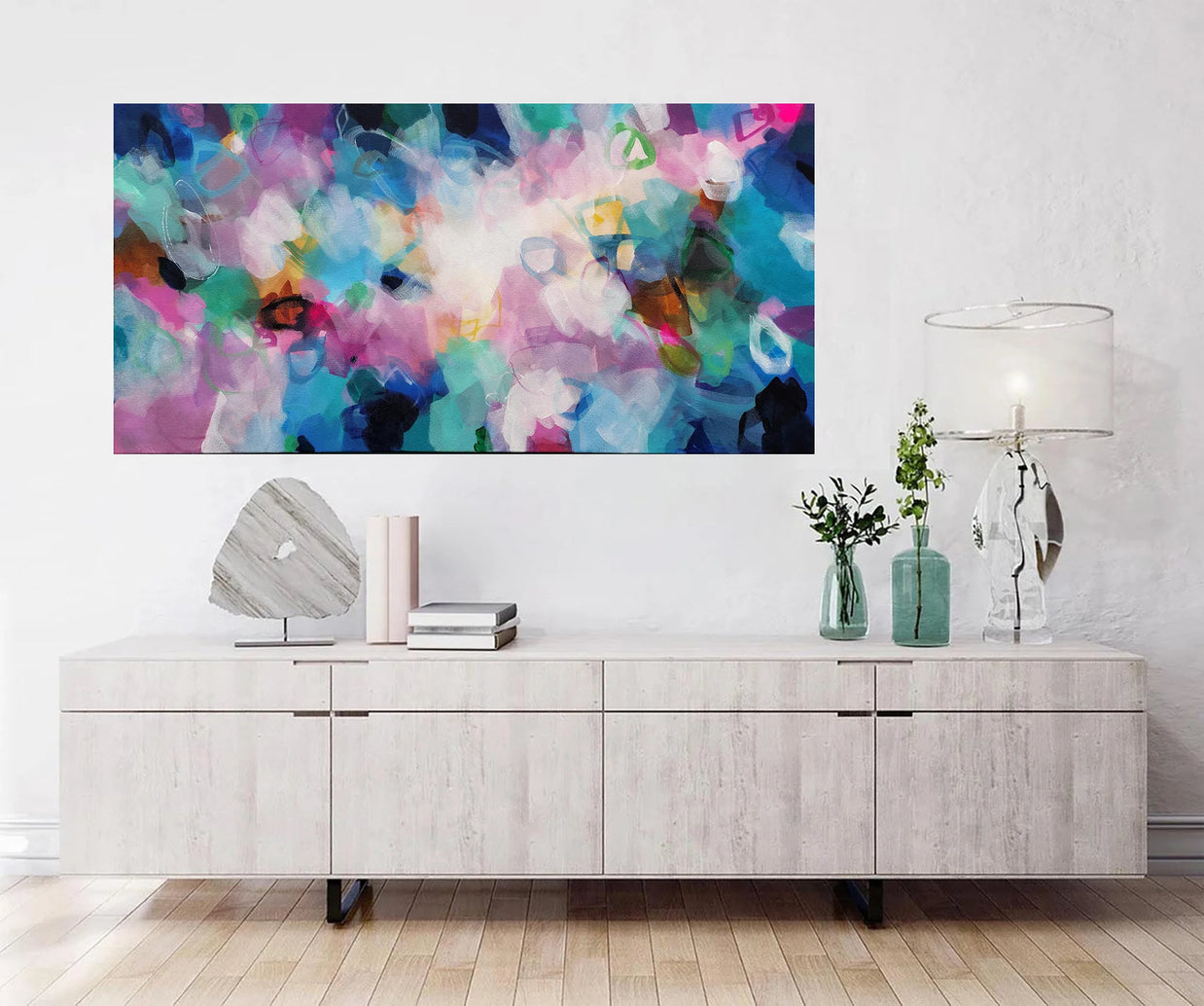 Modern living room with a colorful abstract painting above a wooden cabinet.