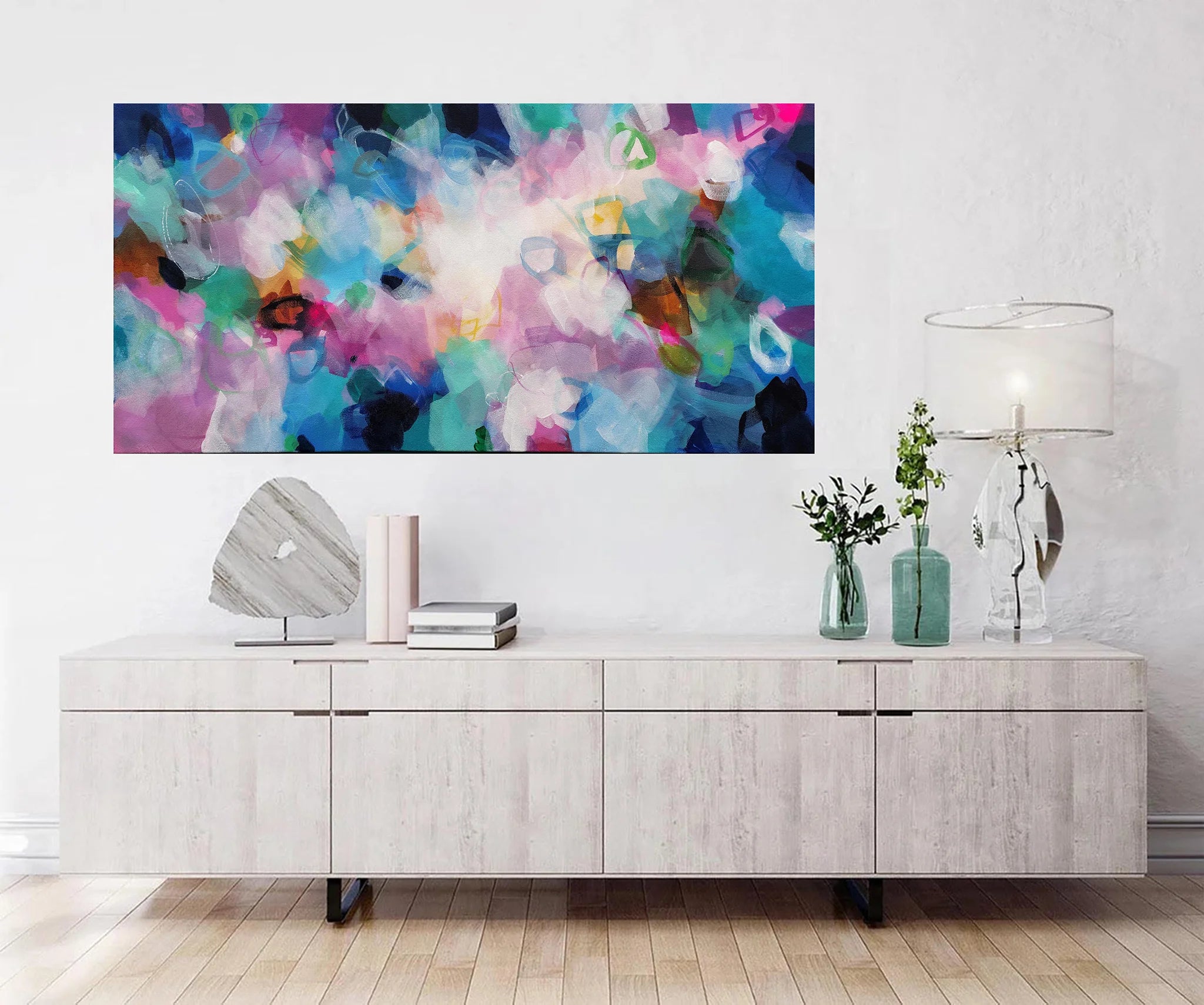 Modern living room with a colorful abstract painting above a wooden cabinet.