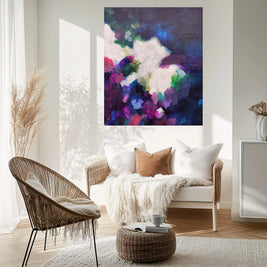 Living room with a wicker chair, white sofa, and abstract painting on the wall.
