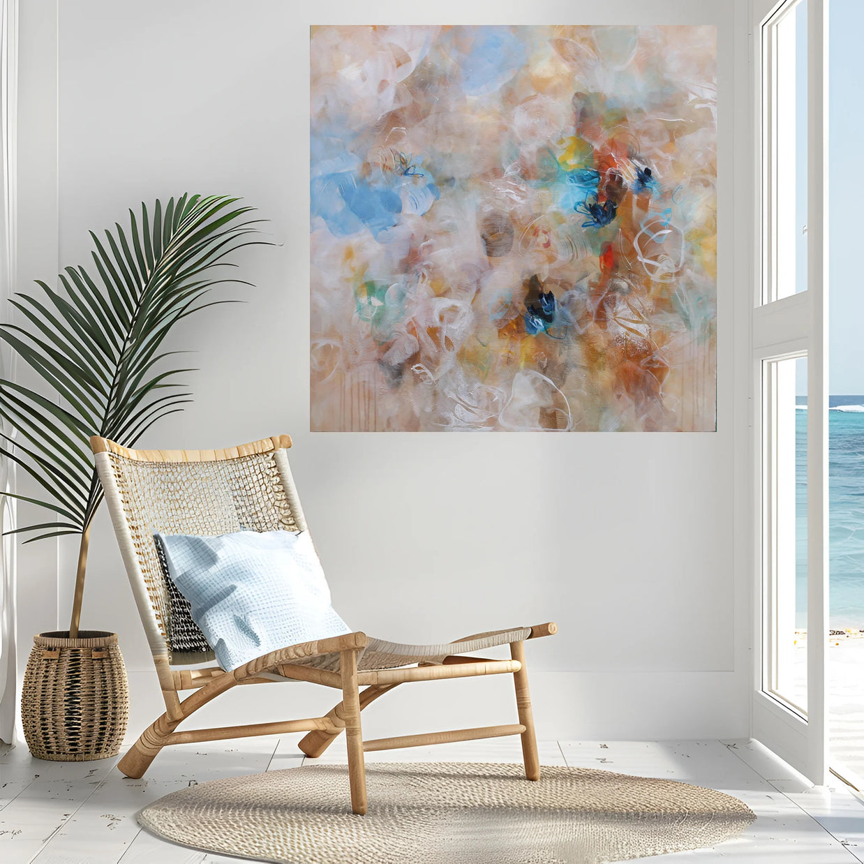 Modern interior with a wicker chair, abstract painting, and view of the ocean.