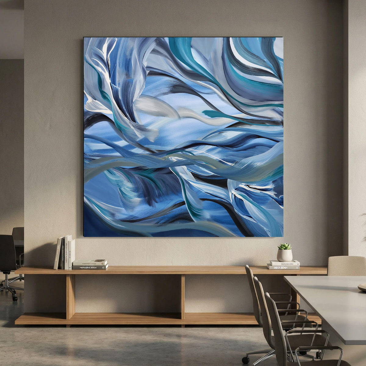 Large square abstract wall art featuring flowing blue, white, and gray brushstrokes, displayed above a wooden console in a modern office or dining room setting.