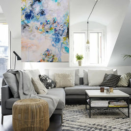 Colourful blue, white, yellow and green abstract painting hanging on wall above sofa