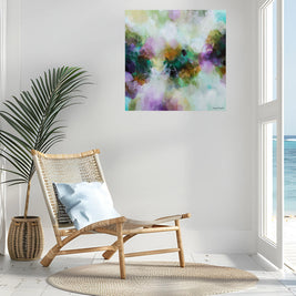 Colorful abstract painting on a wall above a wicker chair with a plant and rug in a room with a view of water.