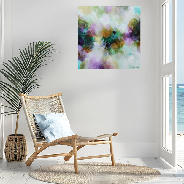 Colorful abstract painting on a wall above a wicker chair with a plant and rug in a room with a view of water.